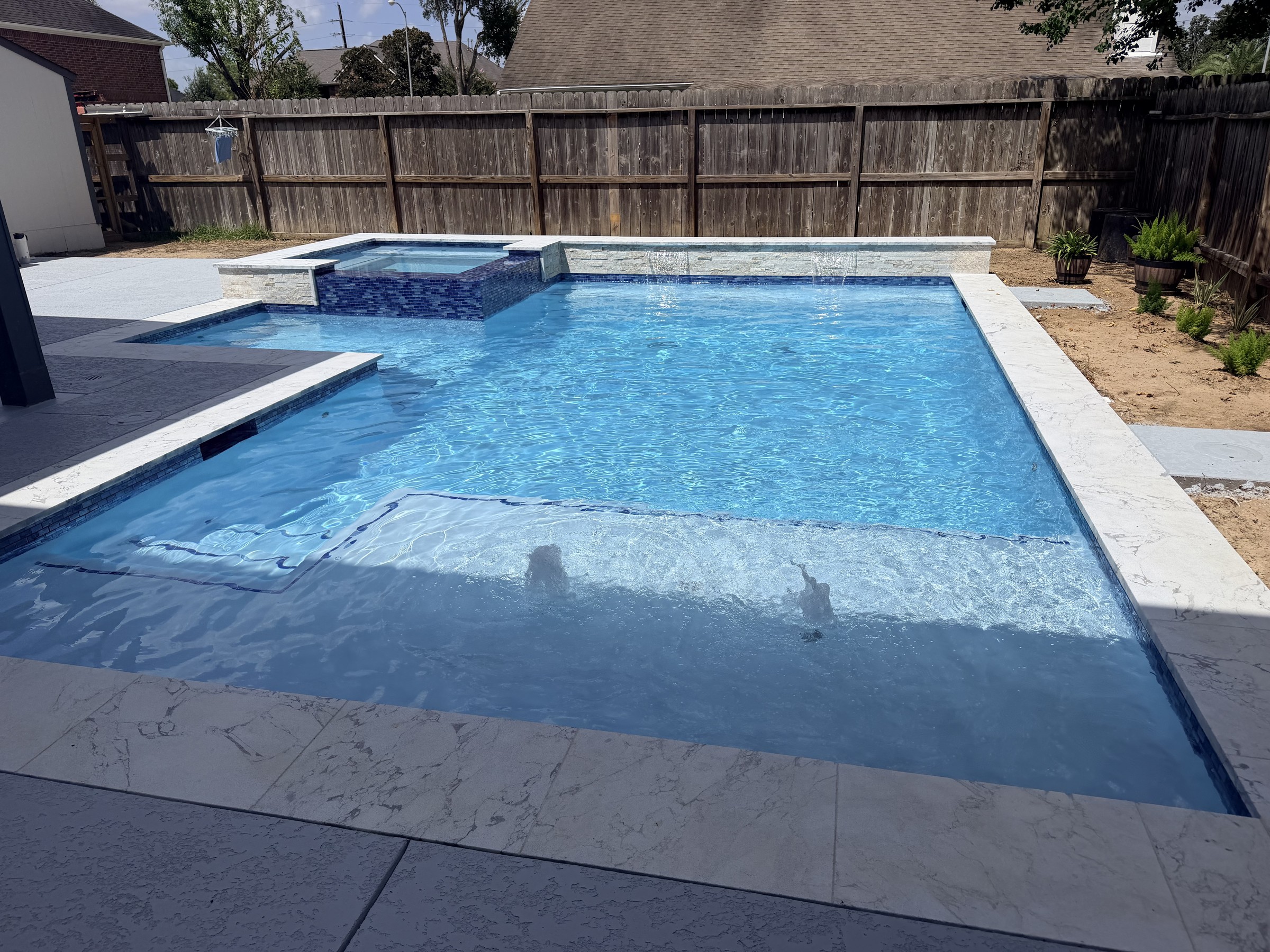 Pool with a raised spa, tanning ledge and sheer descent waterfalls built by Mango Pool & Spa in Katy, Texas