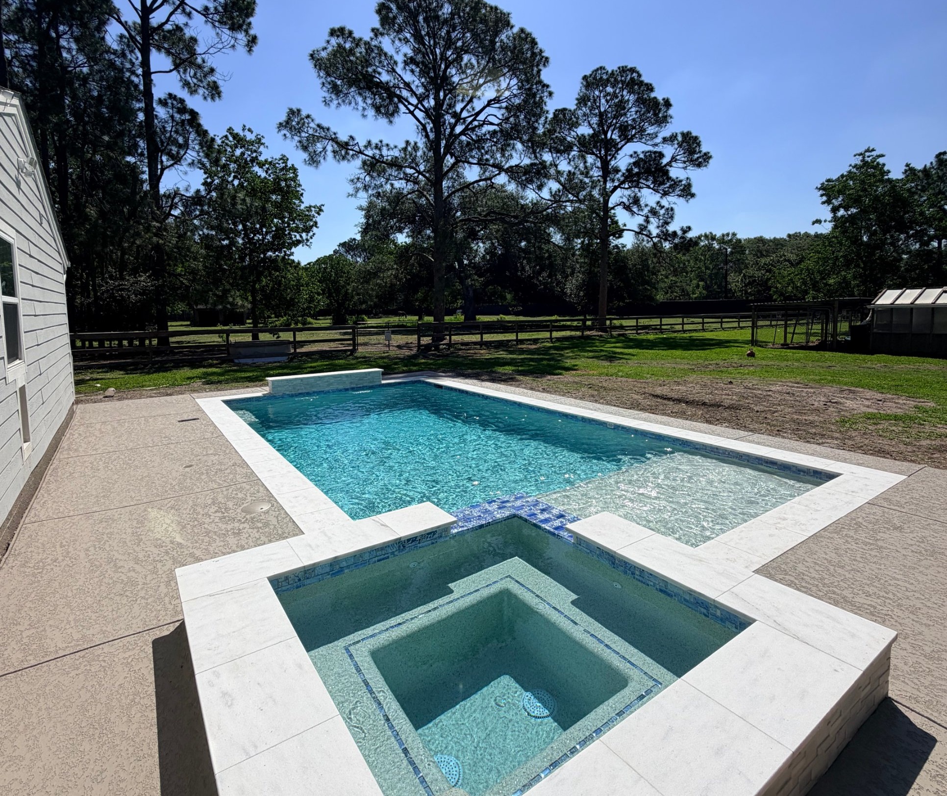 Raised spa with blue glass tile next to a rectangular pool built by Mango Pool & Spa in Houston, Texas