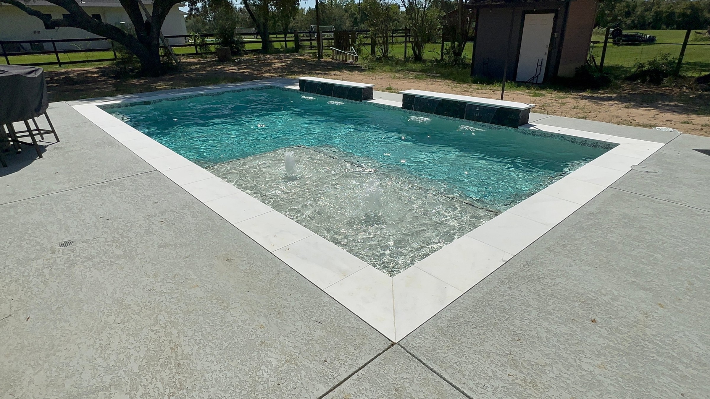 Rectangular pool with tanning ledge, bubblers and sheer descents built by Mango Pool & Spa in Fulshear, Texas